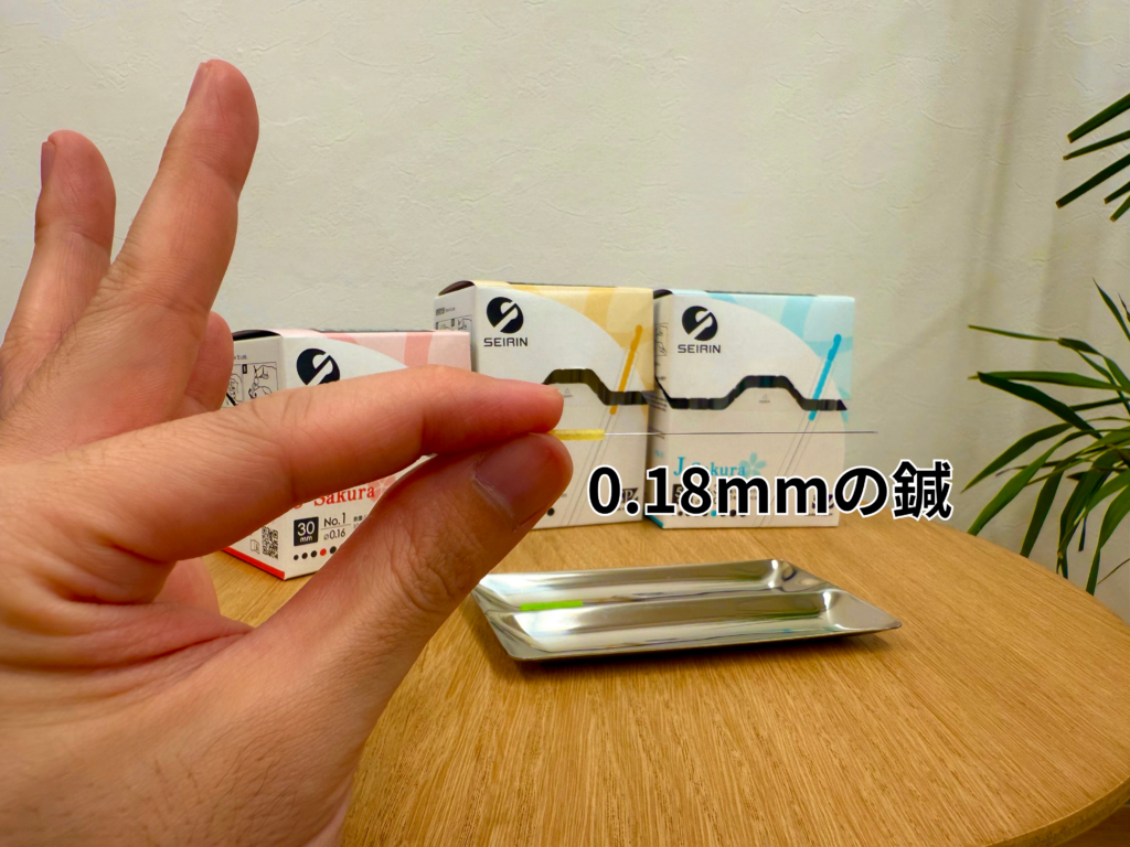日野駅前やまぐち鍼治療院による、鍼の太さ説明の写真。手に持っているのはセイリンの0.18ミリの鍼。ディスポーザブル（使い捨て）で衛生的にも安心。